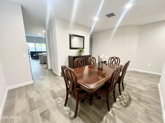dining area with baseboards, light wood-style floors, and visible vents