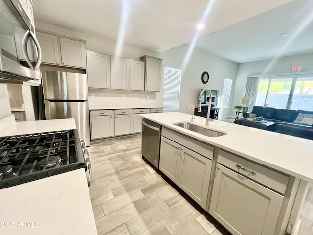 kitchen featuring a sink, open floor plan, gray cabinets, and appliances with stainless steel finishes