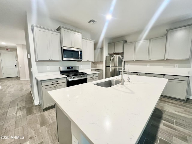 kitchen with light wood-type flooring, stainless steel appliances, visible vents, and a sink