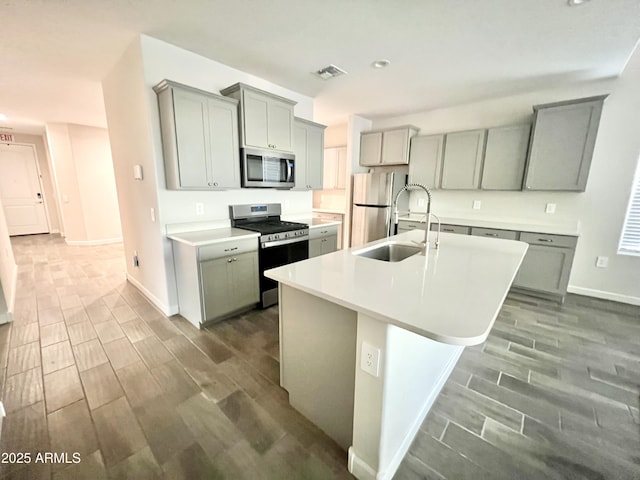 kitchen featuring visible vents, wood tiled floor, appliances with stainless steel finishes, and gray cabinetry