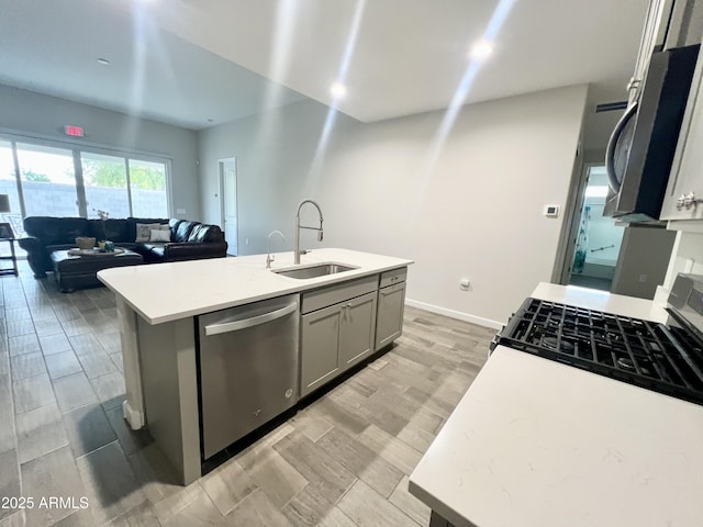 kitchen with a sink, stainless steel appliances, light countertops, light wood-style floors, and gray cabinetry