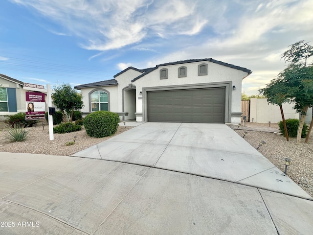 view of front of property featuring fence, a garage, stucco siding, and driveway