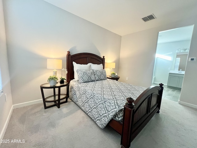 carpeted bedroom featuring ensuite bathroom, baseboards, and visible vents