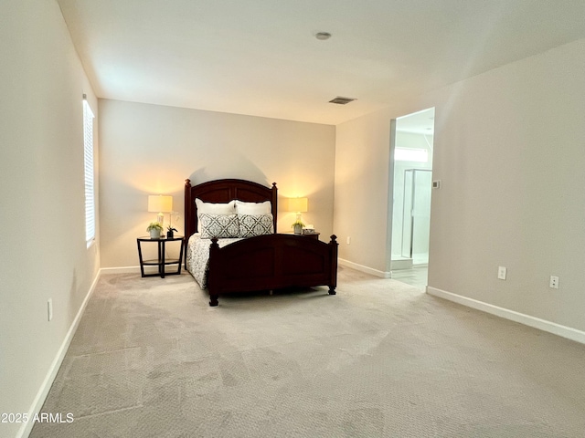carpeted bedroom featuring ensuite bathroom, visible vents, and baseboards