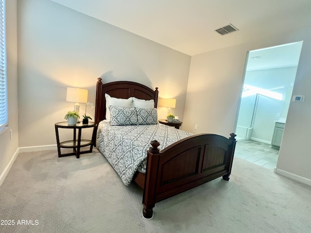 bedroom featuring ensuite bathroom, visible vents, baseboards, and light carpet
