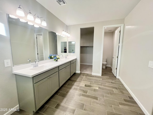 full bath featuring baseboards, wood tiled floor, visible vents, and a sink