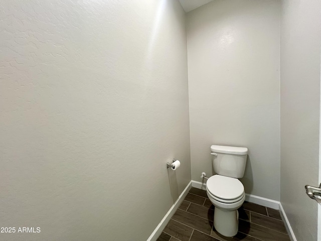 bathroom featuring toilet, baseboards, and wood finish floors