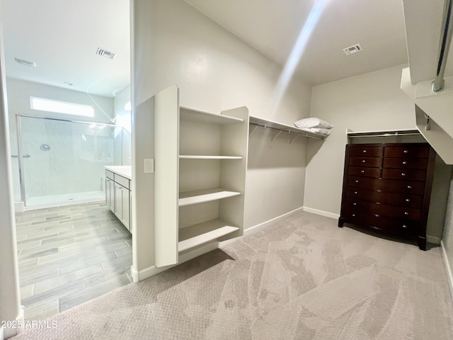 walk in closet with visible vents and light colored carpet