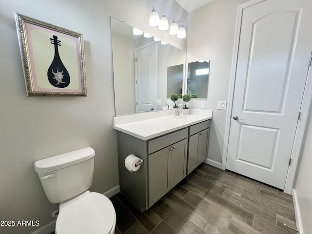 bathroom with toilet, baseboards, vanity, and wood tiled floor