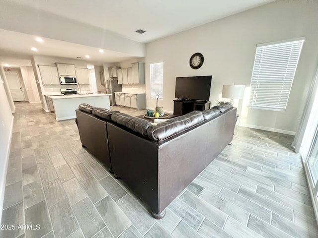 living room featuring visible vents, baseboards, wood finish floors, and recessed lighting