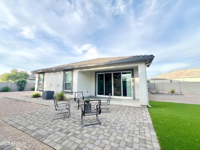 back of property with a patio area, stucco siding, a fenced backyard, a lawn, and central AC unit