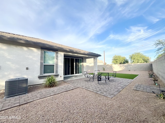 rear view of house featuring central AC unit, stucco siding, a patio area, and a fenced backyard