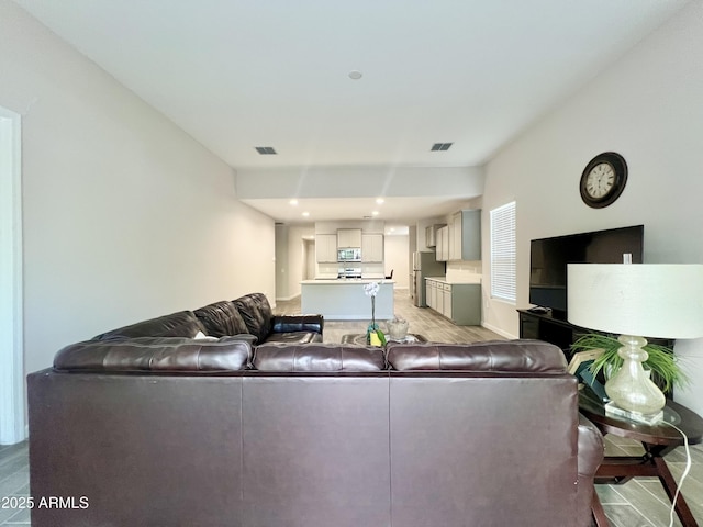 living area with light wood-style flooring and visible vents