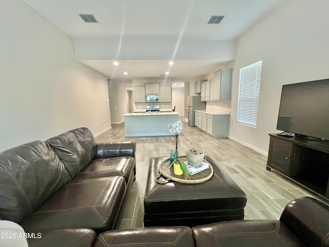 living room with baseboards, recessed lighting, light wood-style floors, and visible vents