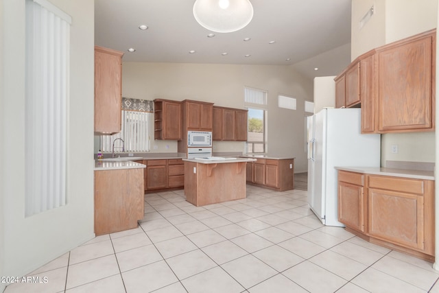 kitchen featuring a breakfast bar area, sink, a kitchen island, white appliances, and light tile patterned floors