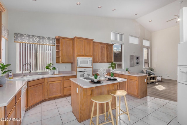 kitchen with white appliances, light countertops, a kitchen island, and a sink