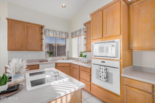 kitchen featuring lofted ceiling, light countertops, light tile patterned flooring, a sink, and white appliances