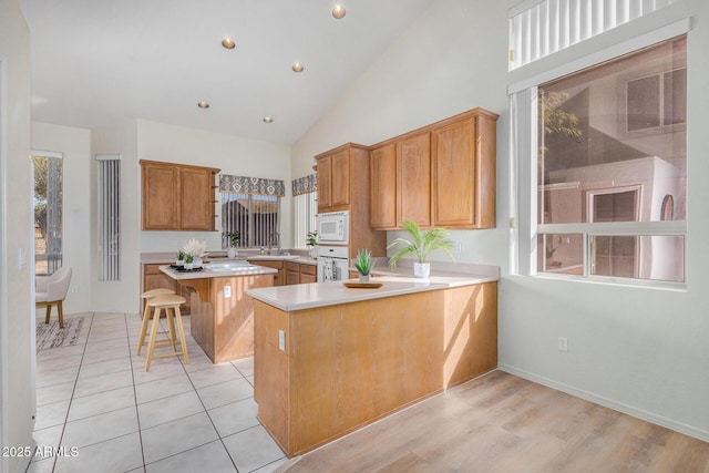 kitchen with white appliances, light countertops, a peninsula, and a kitchen bar