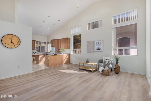 kitchen featuring brown cabinetry, white microwave, open floor plan, a peninsula, and light wood-type flooring