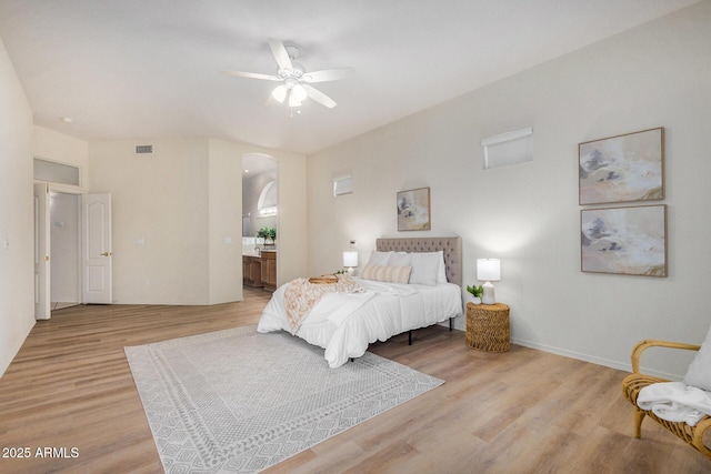 bedroom with visible vents, arched walkways, baseboards, ensuite bathroom, and light wood-style floors