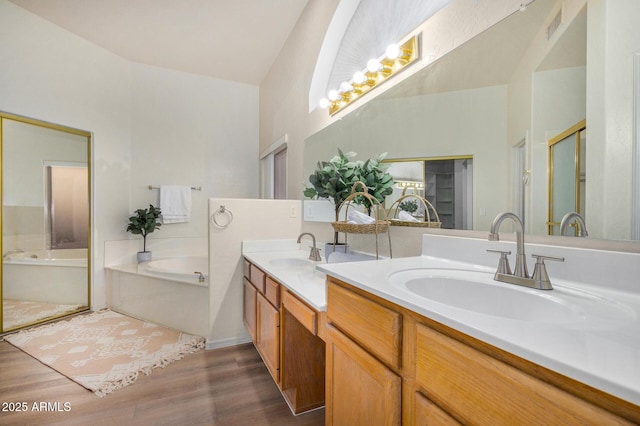 full bath featuring double vanity, a garden tub, a sink, and wood finished floors