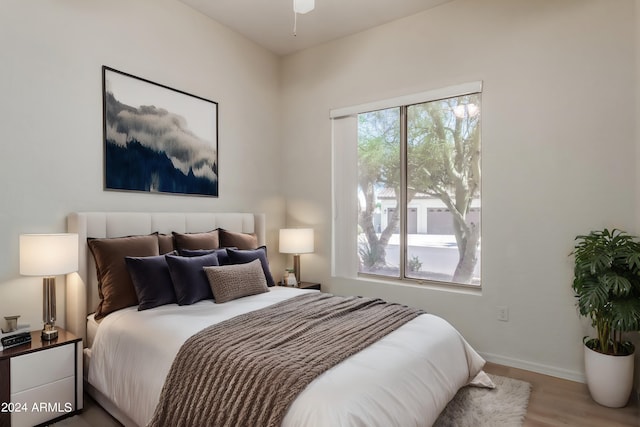 bedroom with multiple windows, light wood-style flooring, and baseboards