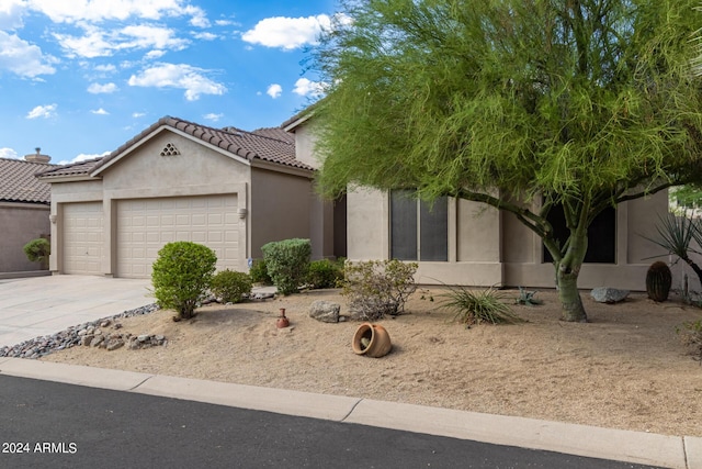 view of front of property with concrete driveway, a tile roof, an attached garage, and stucco siding