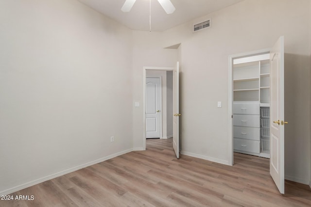 unfurnished bedroom with light wood-type flooring, a walk in closet, visible vents, and baseboards