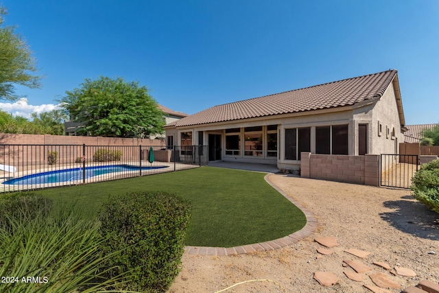 back of house featuring a lawn, a fenced backyard, a fenced in pool, and stucco siding