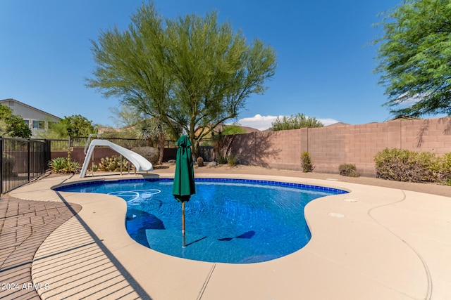 view of swimming pool with a water slide and a patio area