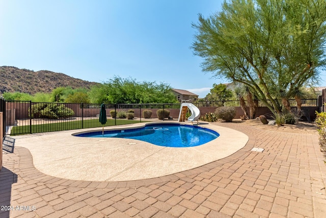 view of swimming pool with a water slide, a fenced backyard, a mountain view, a fenced in pool, and a patio area