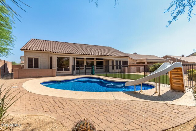 back of house featuring a lawn, a fenced in pool, and a patio area