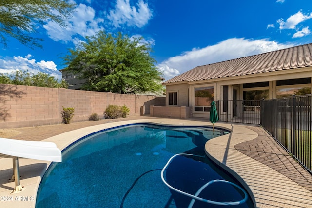 view of swimming pool featuring a patio, a water slide, a fenced backyard, and a fenced in pool