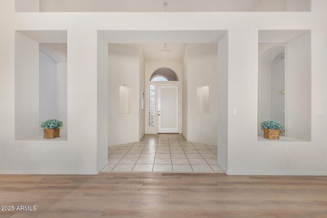 unfurnished living room with high vaulted ceiling, light wood-type flooring, and ceiling fan with notable chandelier