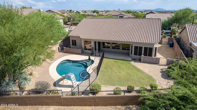 back of property with a fenced in pool, a patio, a fenced backyard, a tiled roof, and a yard