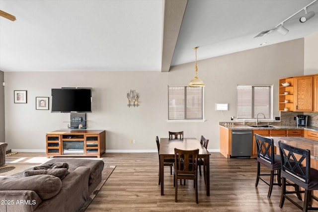 dining space featuring track lighting, vaulted ceiling with beams, wood-type flooring, and sink