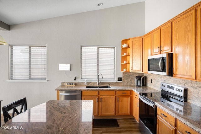 kitchen with stainless steel appliances, dark wood-type flooring, light stone countertops, and sink