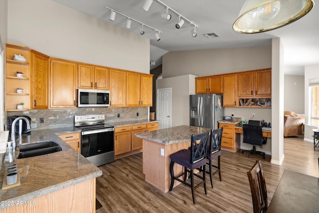 kitchen featuring sink, a kitchen island, light stone countertops, and appliances with stainless steel finishes