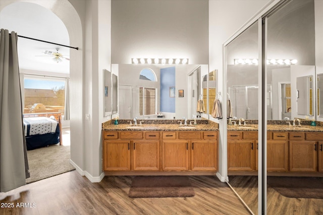 bathroom featuring wood-type flooring, vanity, ceiling fan, a shower with door, and a high ceiling