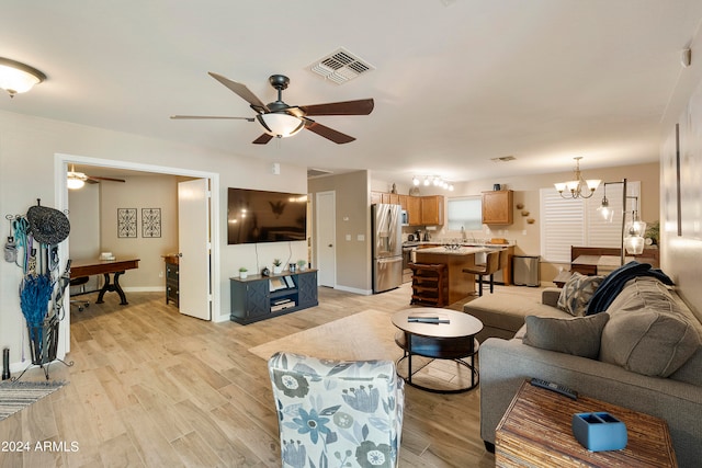 living room featuring ceiling fan with notable chandelier and light wood-type flooring