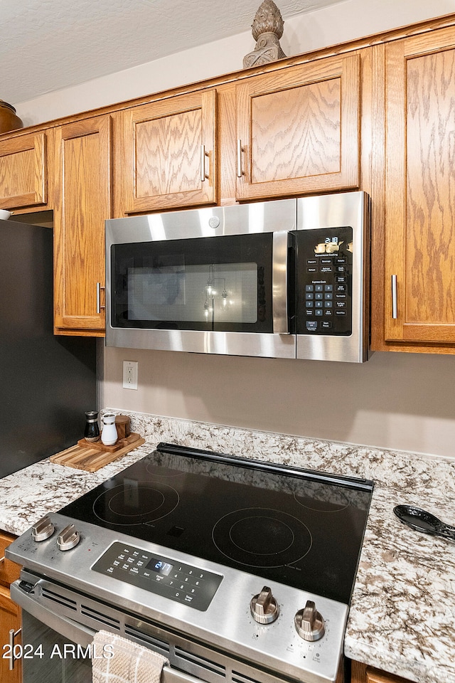 kitchen with light stone counters and appliances with stainless steel finishes