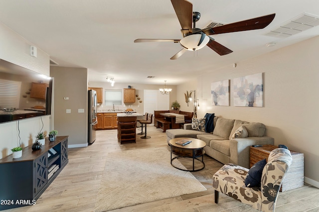 living room featuring sink, ceiling fan with notable chandelier, and light wood-type flooring