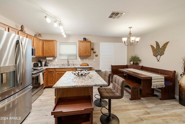 kitchen featuring hanging light fixtures, a kitchen island, sink, light hardwood / wood-style floors, and stainless steel appliances