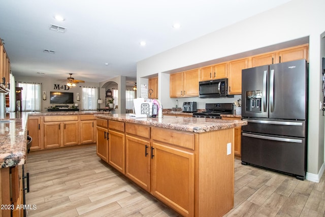 kitchen featuring an island with sink, range, kitchen peninsula, stainless steel refrigerator with ice dispenser, and light wood-type flooring