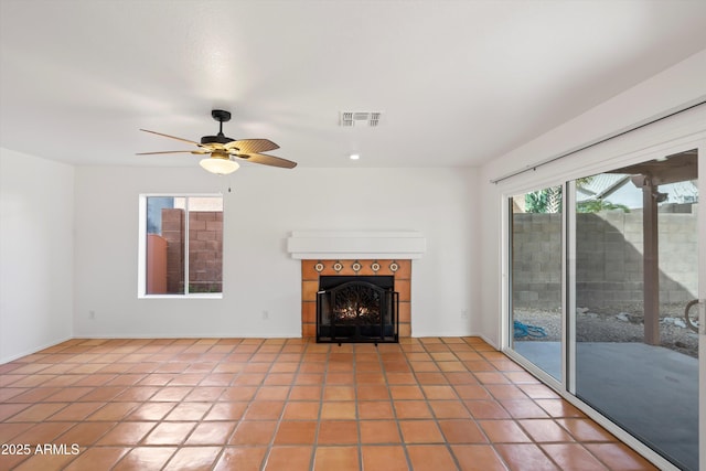 unfurnished living room with a tiled fireplace, visible vents, tile patterned flooring, and ceiling fan