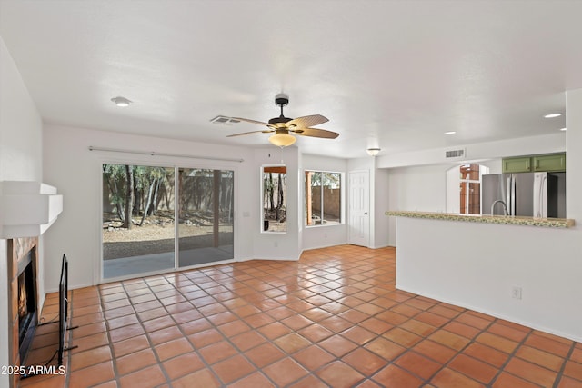 unfurnished living room featuring tile patterned floors, visible vents, a ceiling fan, and a premium fireplace