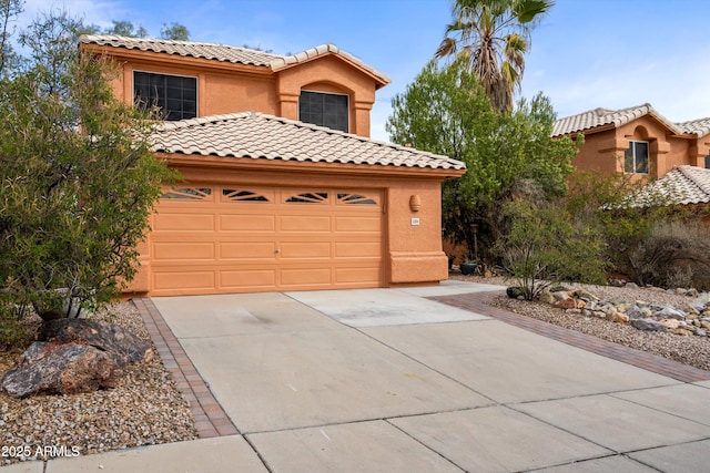 mediterranean / spanish house featuring driveway, stucco siding, a tiled roof, and an attached garage