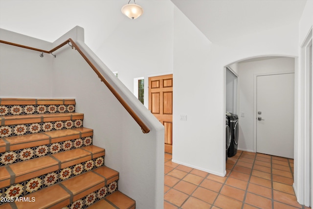 stairs featuring tile patterned floors, arched walkways, and separate washer and dryer