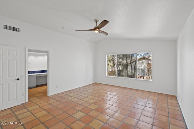 tiled spare room featuring visible vents, vaulted ceiling, and a ceiling fan