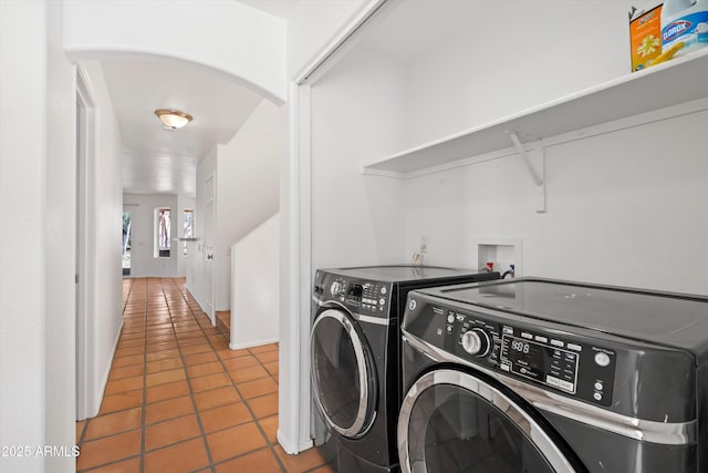 washroom with washer and dryer, arched walkways, and tile patterned flooring